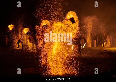 Silhouette zweier Feuerkünstler mit funkelndem Feuerwehrpersonal, das am Nachthimmel ausbricht und die Energie und Kunst der Feuermanipulation während eines Outdours zeigt Stockfoto