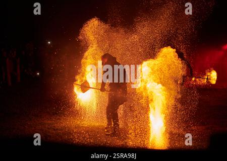Silhouette zweier Feuerkünstler mit funkelndem Feuerwehrpersonal, das am Nachthimmel ausbricht und die Energie und Kunst der Feuermanipulation während eines Outdours zeigt Stockfoto