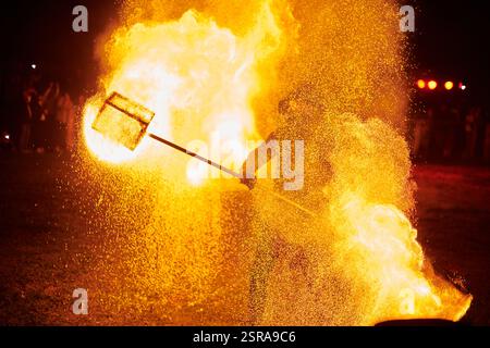Silhouette zweier Feuerkünstler mit funkelndem Feuerwehrpersonal, das am Nachthimmel ausbricht und die Energie und Kunst der Feuermanipulation während eines Outdours zeigt Stockfoto