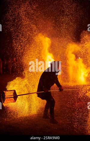 Silhouette zweier Feuerkünstler mit funkelndem Feuerwehrpersonal, das am Nachthimmel ausbricht und die Energie und Kunst der Feuermanipulation während eines Outdours zeigt Stockfoto
