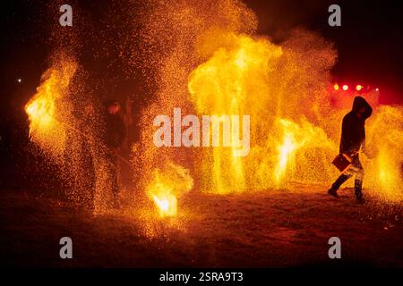 Silhouette zweier Feuerkünstler mit funkelndem Feuerwehrpersonal, das am Nachthimmel ausbricht und die Energie und Kunst der Feuermanipulation während eines Outdours zeigt Stockfoto