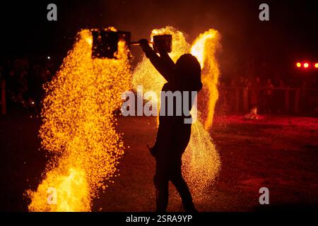 Silhouette zweier Feuerkünstler mit funkelndem Feuerwehrpersonal, das am Nachthimmel ausbricht und die Energie und Kunst der Feuermanipulation während eines Outdours zeigt Stockfoto