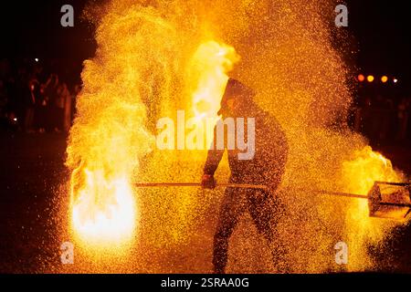 Silhouette zweier Feuerkünstler mit funkelndem Feuerwehrpersonal, das am Nachthimmel ausbricht und die Energie und Kunst der Feuermanipulation während eines Outdours zeigt Stockfoto