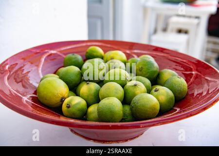 Limettenfrüchte auf dem Tisch in einer roten Schüssel Stockfoto