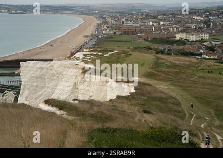 Blick auf die weißen Klippen von Seaford, Großbritannien, mit Menschen am Strand und Wanderwegen auf den Klippen. Sonniger Tag. Stockfoto
