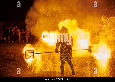 Silhouette zweier Feuerkünstler mit funkelndem Feuerwehrpersonal, das am Nachthimmel ausbricht und die Energie und Kunst der Feuermanipulation während eines Outdours zeigt Stockfoto