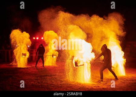 Silhouette zweier Feuerkünstler mit funkelndem Feuerwehrpersonal, das am Nachthimmel ausbricht und die Energie und Kunst der Feuermanipulation während eines Outdours zeigt Stockfoto