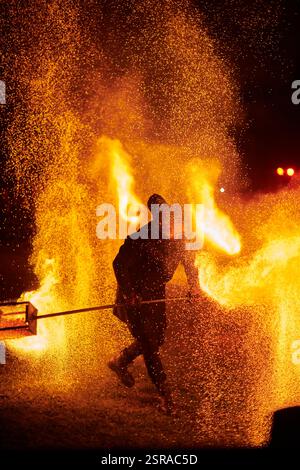 Silhouette zweier Feuerkünstler mit funkelndem Feuerwehrpersonal, das am Nachthimmel ausbricht und die Energie und Kunst der Feuermanipulation während eines Outdours zeigt Stockfoto