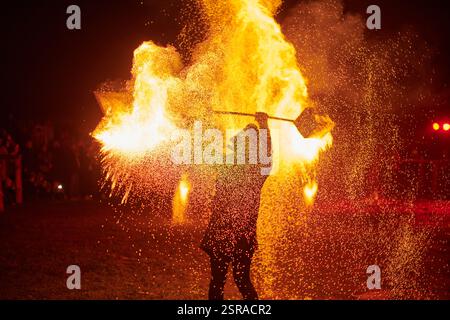 Silhouette zweier Feuerkünstler mit funkelndem Feuerwehrpersonal, das am Nachthimmel ausbricht und die Energie und Kunst der Feuermanipulation während eines Outdours zeigt Stockfoto