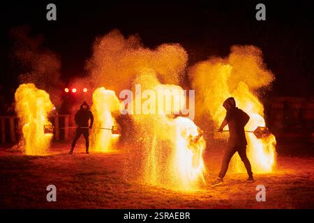 Silhouette zweier Feuerkünstler mit funkelndem Feuerwehrpersonal, das am Nachthimmel ausbricht und die Energie und Kunst der Feuermanipulation während eines Outdours zeigt Stockfoto
