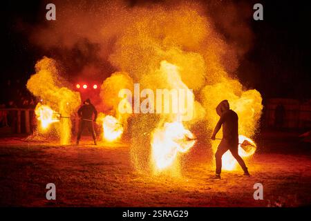 Silhouette zweier Feuerkünstler mit funkelndem Feuerwehrpersonal, das am Nachthimmel ausbricht und die Energie und Kunst der Feuermanipulation während eines Outdours zeigt Stockfoto