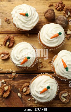 Leckere Karotten-Cupcakes und Walnüsse auf Holztisch, flach gelegt Stockfoto