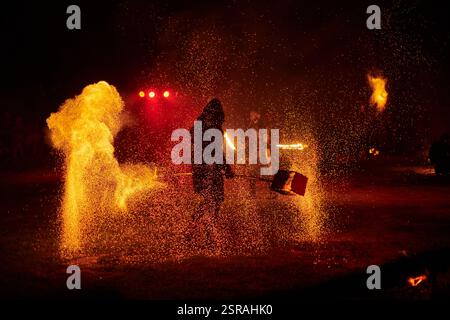 Silhouette zweier Feuerkünstler mit funkelndem Feuerwehrpersonal, das am Nachthimmel ausbricht und die Energie und Kunst der Feuermanipulation während eines Outdours zeigt Stockfoto