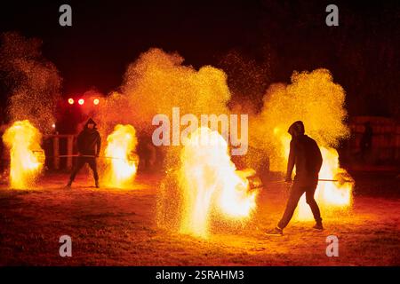 Silhouette zweier Feuerkünstler mit funkelndem Feuerwehrpersonal, das am Nachthimmel ausbricht und die Energie und Kunst der Feuermanipulation während eines Outdours zeigt Stockfoto