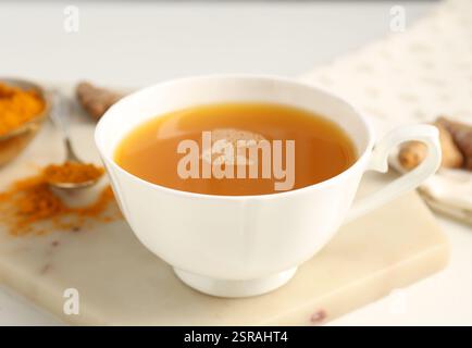 Aromatischer Kurkuma-Tee, Pulver und Rhizome auf weißem Tisch, Nahaufnahme Stockfoto