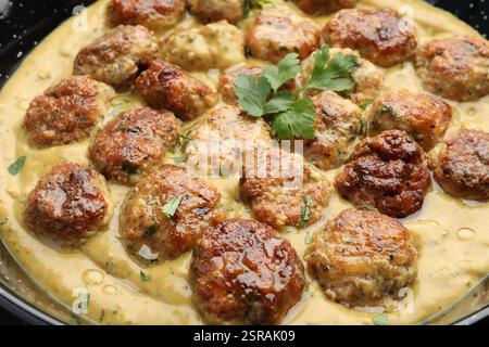 Leckere Fleischbällchen mit Soße und Kräutern in der Pfanne, Großaufnahme Stockfoto