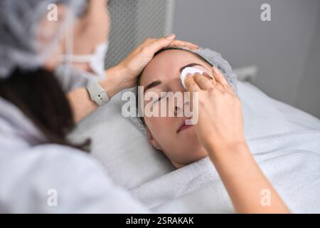 Junge Frau erhält eine entspannende Gesichtsbehandlung im modernen Spa. Ruhe und Ruhe mit Schwerpunkt auf Verjüngung und Hautpflege Wellness Stockfoto