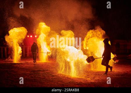 Silhouette zweier Feuerkünstler mit funkelndem Feuerwehrpersonal, das am Nachthimmel ausbricht und die Energie und Kunst der Feuermanipulation während eines Outdours zeigt Stockfoto