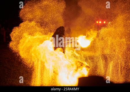 Silhouette zweier Feuerkünstler mit funkelndem Feuerwehrpersonal, das am Nachthimmel ausbricht und die Energie und Kunst der Feuermanipulation während eines Outdours zeigt Stockfoto