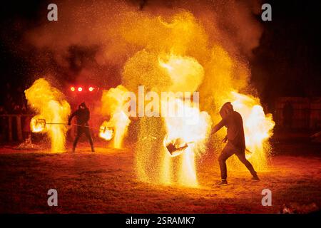 Silhouette zweier Feuerkünstler mit funkelndem Feuerwehrpersonal, das am Nachthimmel ausbricht und die Energie und Kunst der Feuermanipulation während eines Outdours zeigt Stockfoto