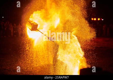 Silhouette zweier Feuerkünstler mit funkelndem Feuerwehrpersonal, das am Nachthimmel ausbricht und die Energie und Kunst der Feuermanipulation während eines Outdours zeigt Stockfoto
