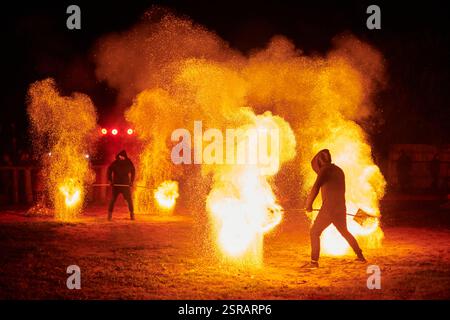 Silhouette zweier Feuerkünstler mit funkelndem Feuerwehrpersonal, das am Nachthimmel ausbricht und die Energie und Kunst der Feuermanipulation während eines Outdours zeigt Stockfoto