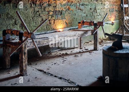 Hölzerne, mittelalterliche Folterständer mit Seilen und Kurbeln in einem von Steinmauern umgebenen Verlies, beleuchtet von dunkler Beleuchtung, symbolisiert eine düstere Erinnerung an historische Grausamkeiten Stockfoto