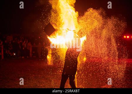 Silhouette zweier Feuerkünstler mit funkelndem Feuerwehrpersonal, das am Nachthimmel ausbricht und die Energie und Kunst der Feuermanipulation während eines Outdours zeigt Stockfoto