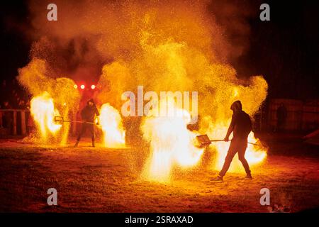Silhouette zweier Feuerkünstler mit funkelndem Feuerwehrpersonal, das am Nachthimmel ausbricht und die Energie und Kunst der Feuermanipulation während eines Outdours zeigt Stockfoto
