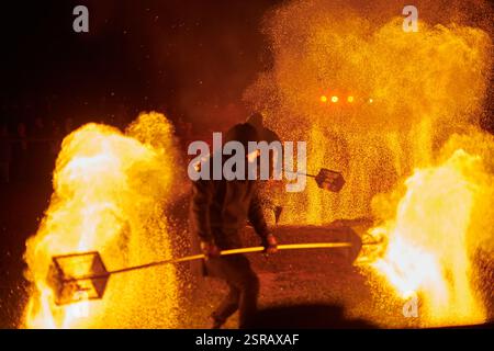 Silhouette zweier Feuerkünstler mit funkelndem Feuerwehrpersonal, das am Nachthimmel ausbricht und die Energie und Kunst der Feuermanipulation während eines Outdours zeigt Stockfoto