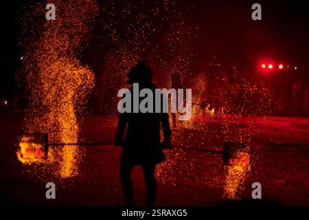 Silhouette zweier Feuerkünstler mit funkelndem Feuerwehrpersonal, das am Nachthimmel ausbricht und die Energie und Kunst der Feuermanipulation während eines Outdours zeigt Stockfoto