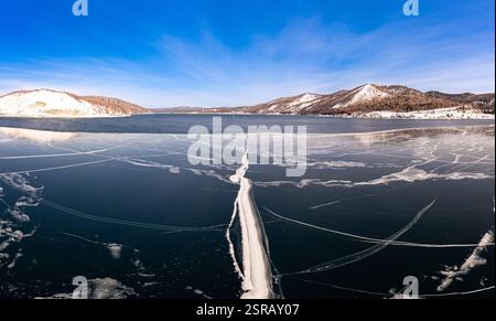 Blick von oben auf den Blue Clear Ice Lake Baikal. Rissüberzug auf gefrorenem Wasser. Kalte Winterlandschaft mit Bergen, sonniger Tag, Natur Stockfoto