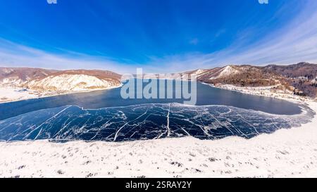 Blick von oben auf den Blue Clear Ice Lake Baikal. Rissüberzug auf gefrorenem Wasser. Kalte Winterlandschaft mit Bergen, sonniger Tag, Natur Stockfoto