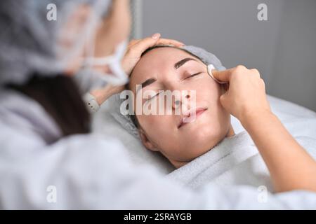 Junge Frau erhält eine entspannende Gesichtsbehandlung im modernen Spa. Ruhe und Ruhe mit Schwerpunkt auf Verjüngung und Hautpflege Wellness Stockfoto