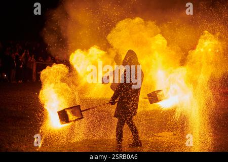 Silhouette zweier Feuerkünstler mit funkelndem Feuerwehrpersonal, das am Nachthimmel ausbricht und die Energie und Kunst der Feuermanipulation während eines Outdours zeigt Stockfoto