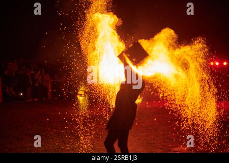 Silhouette zweier Feuerkünstler mit funkelndem Feuerwehrpersonal, das am Nachthimmel ausbricht und die Energie und Kunst der Feuermanipulation während eines Outdours zeigt Stockfoto