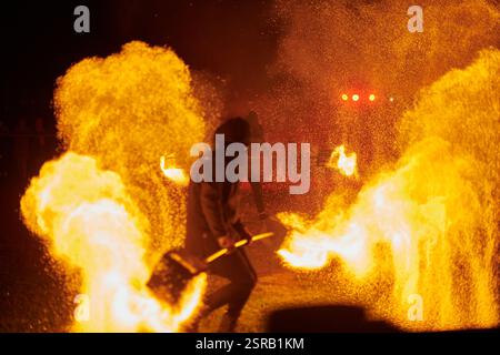 Silhouette zweier Feuerkünstler mit funkelndem Feuerwehrpersonal, das am Nachthimmel ausbricht und die Energie und Kunst der Feuermanipulation während eines Outdours zeigt Stockfoto