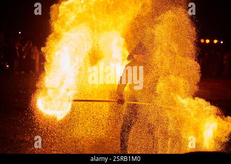 Silhouette zweier Feuerkünstler mit funkelndem Feuerwehrpersonal, das am Nachthimmel ausbricht und die Energie und Kunst der Feuermanipulation während eines Outdours zeigt Stockfoto