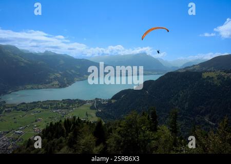 Ein Gleitschirmflieger schwingt hoch über einem atemberaubenden Bergsee und bietet atemberaubende Ausblicke. Das Bild fängt den Nervenkitzel von Abenteuersportarten und landschaftlich reizvollen Landschaften ein. Stockfoto