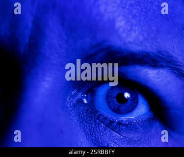 Nahaufnahme eines menschlichen Auges (weiblich Mitte 40, kaukasisch) unter blauem Licht. Stockfoto