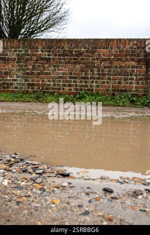 Eine schlammige Pfütze auf einer Auffahrt im Winter in Großbritannien Stockfoto