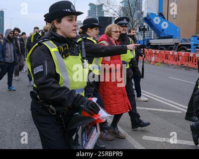 London, Großbritannien. Februar 2025. Eine Frau wird verhaftet und von Polizisten begleitet, die ihr Protestplakat mit den US- und israelischen Fahnen und dem Nazi-Hakenkreuz tragen. Zehntausende marschierten von Whitehall zur US-Botschaft in neun Elmen beim 24. nationalmarsch für Palästina, als sie die von Präsident Donald Trump vorgeschlagenen Pläne für den Gazastreifen ablehnen, in denen er vorschlug, das Territorium zu übernehmen. Quelle: Eleventh Photography/Alamy Live News Stockfoto