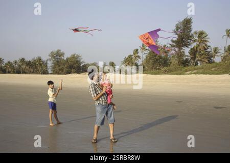 Südasiatischer indischer Vater mit Tochter und Sohn, der Drachen am Meer fliegt, Shiroda, Dist. Sindhudurga, Maharashtra, Indien MR# 703G, 703F, 703D Stockfoto