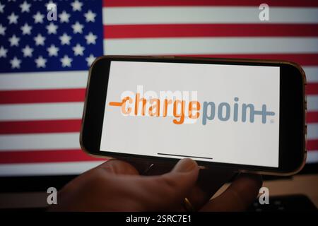 Roosendaal, Niederlande - 15. Februar 2025: Ein Mobiltelefon mit dem Logo von ChargePoint, mit der Flagge der Vereinigten Staaten im Hintergrund Stockfoto