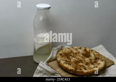 Hüttenkäse-Auflauf mit getrockneten Früchten und Zimt in einem langsamen Herd gekocht und einer Flasche Sauermilch Stockfoto