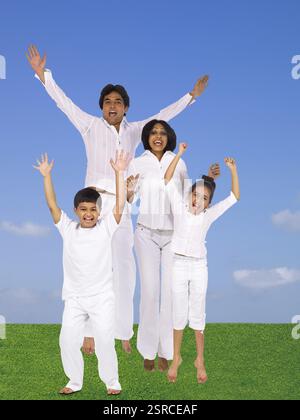 Eltern und Kinder in weißen Kostümen mit Freude Herrn springen Stockfoto