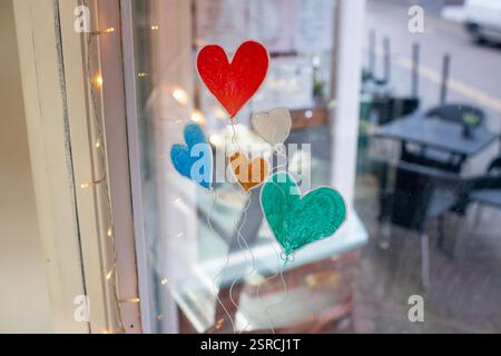 Ein Fenster mit einer Zeichnung von fünf Herzen und Ballons. Die Ballons sind in verschiedenen Farben und die Herzen sind auf dem Fenster gemalt. Die Szene ist jubelnd Stockfoto