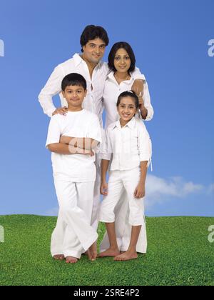 Eltern und Kinder in weißen Kostümen stehen auf dem grünen Rasen Stockfoto