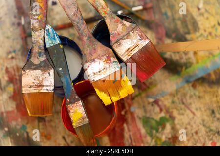 Gebrauchte Pinsel in verschiedenen Farben getaucht, Künstlerpalette. Stockfoto