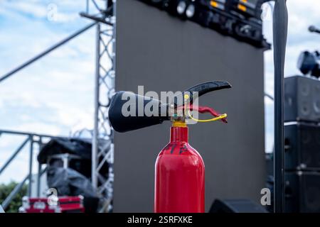 Ein roter Feuerlöscher befindet sich auf einem Metallmast. Die Stange ist Teil einer Bühne, die für ein Konzert eingerichtet wurde Stockfoto